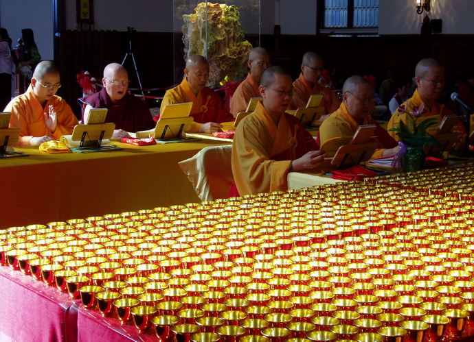 Monastics reciting Tibetan mantra for victims of Hurricane Katrina at Hua Zang Si. The Yun sculpture of Mt. Sumeru is in the background while over a thousand of the daily water offerings are shown in the foreground.
